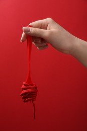 Woman holding fork with shoelace on red background, closeup