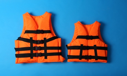 Photo of Orange life jackets on blue background. Personal flotation device