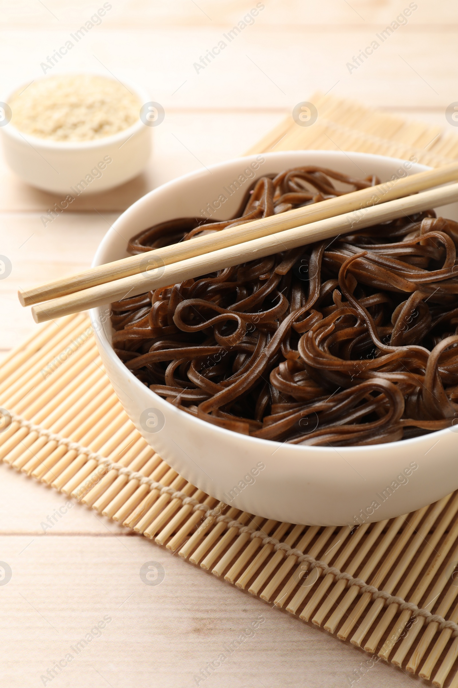 Photo of Tasty buckwheat noodles (soba) with chopsticks on wooden table, closeup