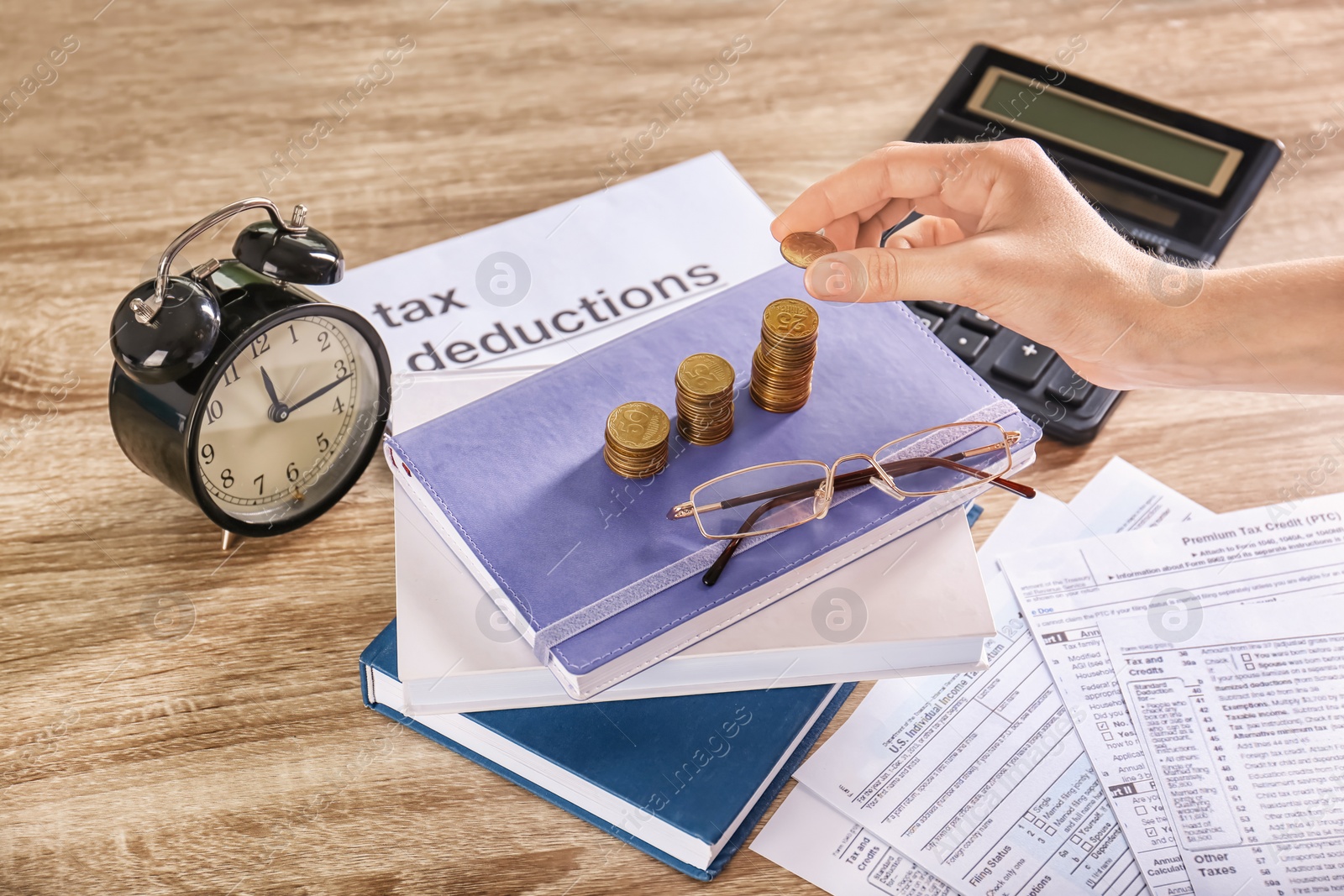 Photo of Woman stacking coins on table. Tax calculation