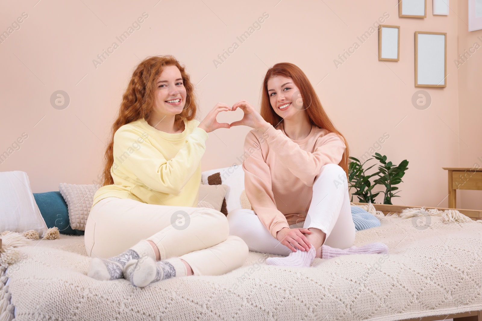 Photo of Portrait of beautiful young redhead sisters in bedroom