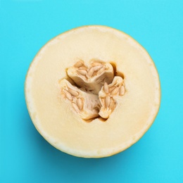 Photo of Half of ripe tasty melon on blue background, top view