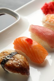 Plate with delicious nigiri sushi and soy sauce on table, closeup