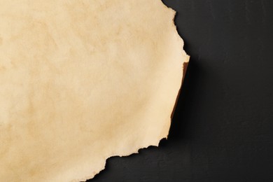 Photo of Sheet of old parchment paper on black wooden table, top view. Space for text