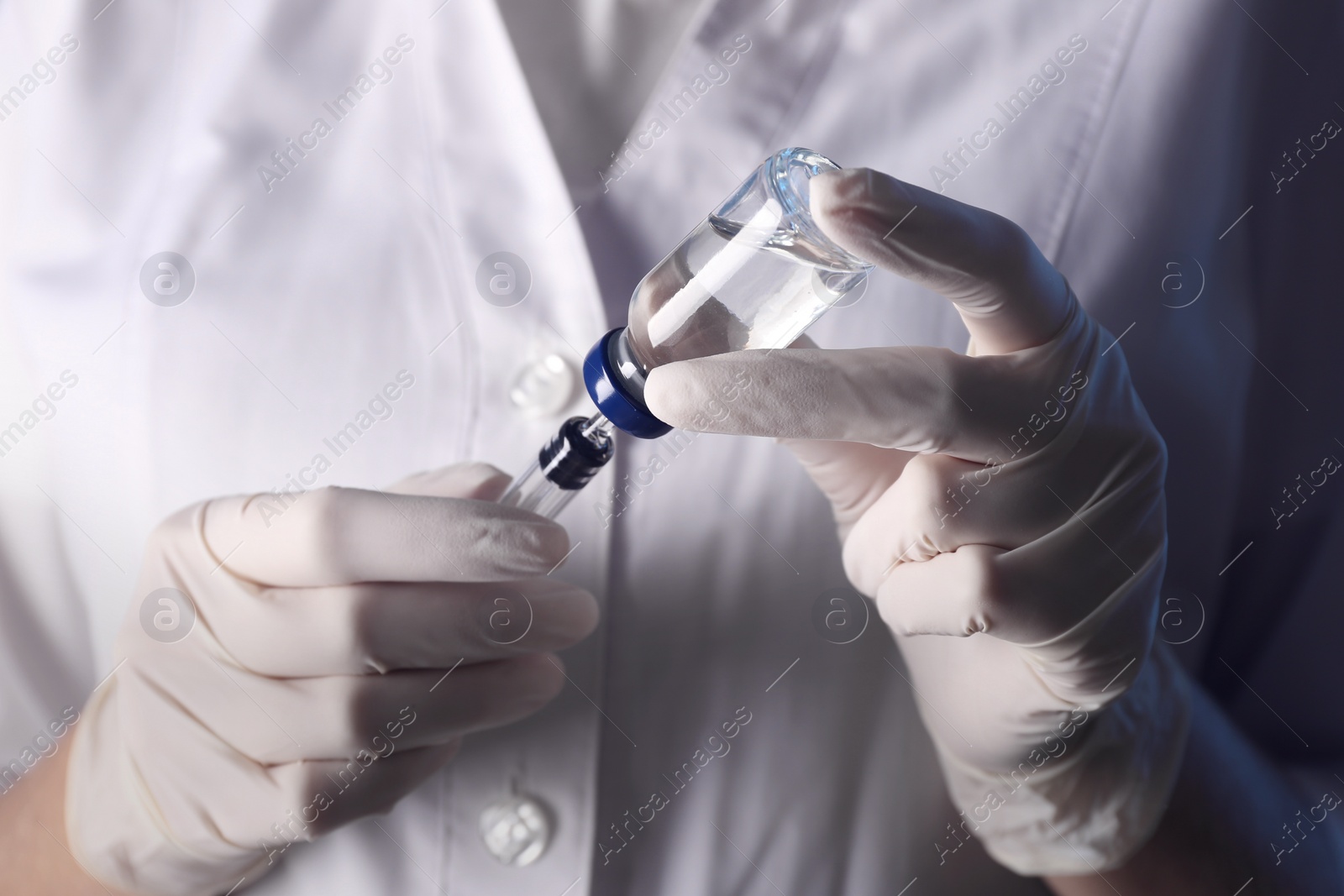 Photo of Doctor filling syringe with vaccine from vial, closeup