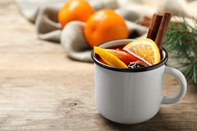 Mug with aromatic mulled wine on wooden table