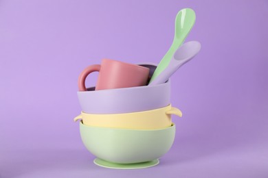 Photo of Set of plastic dishware on violet background. Serving baby food