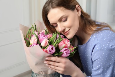 Young woman with bouquet of beautiful tulips indoors