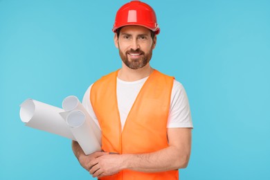 Photo of Architect in hard hat with drafts on light blue background