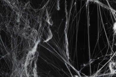 Photo of Creepy white cobweb on black background, closeup