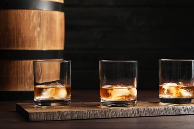 Photo of Glasses of tasty whiskey on table against dark background