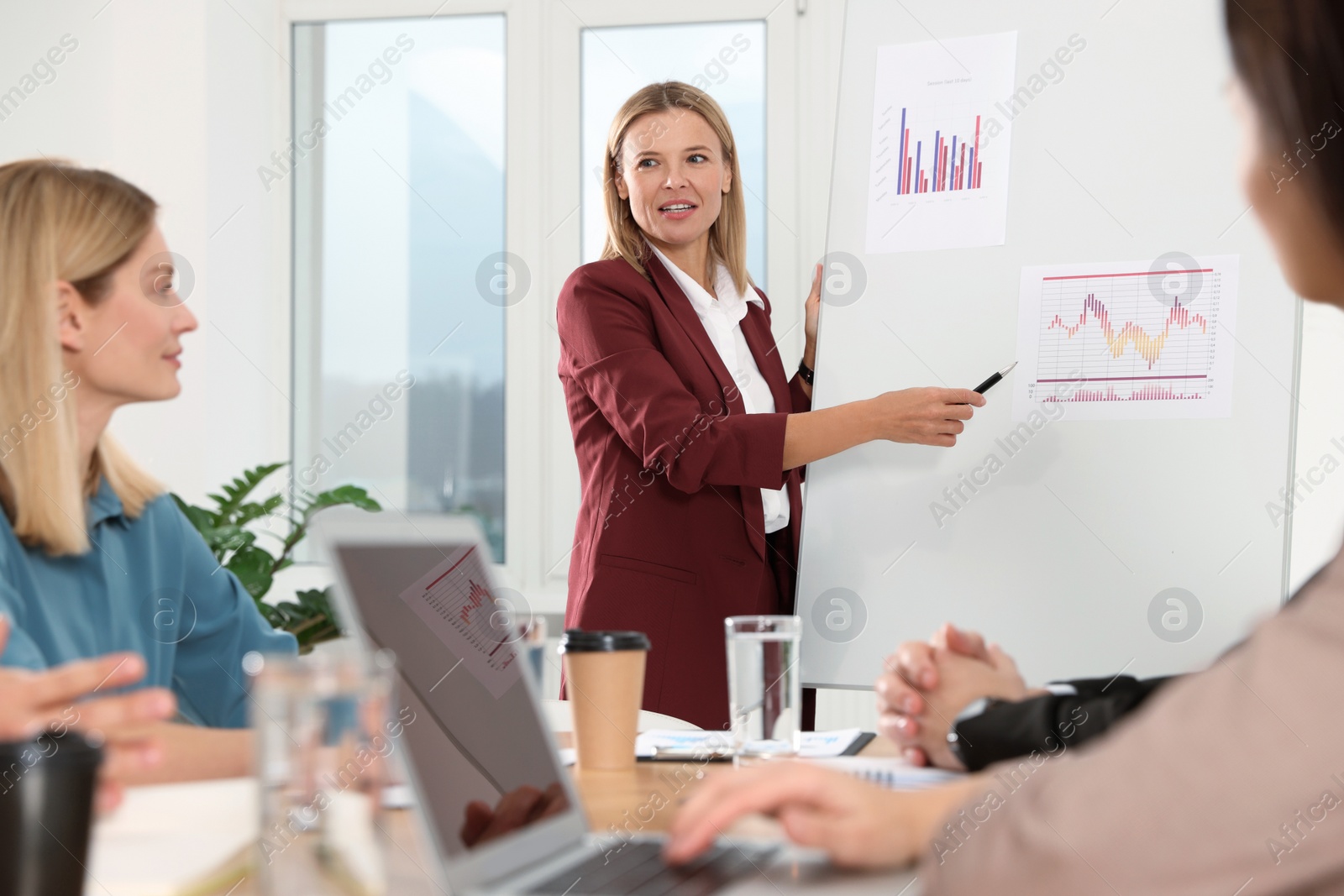 Photo of Businesswoman showing charts near flipchart on meeting in office