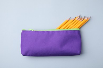 Many sharp pencils in pencil case on light grey background, top view