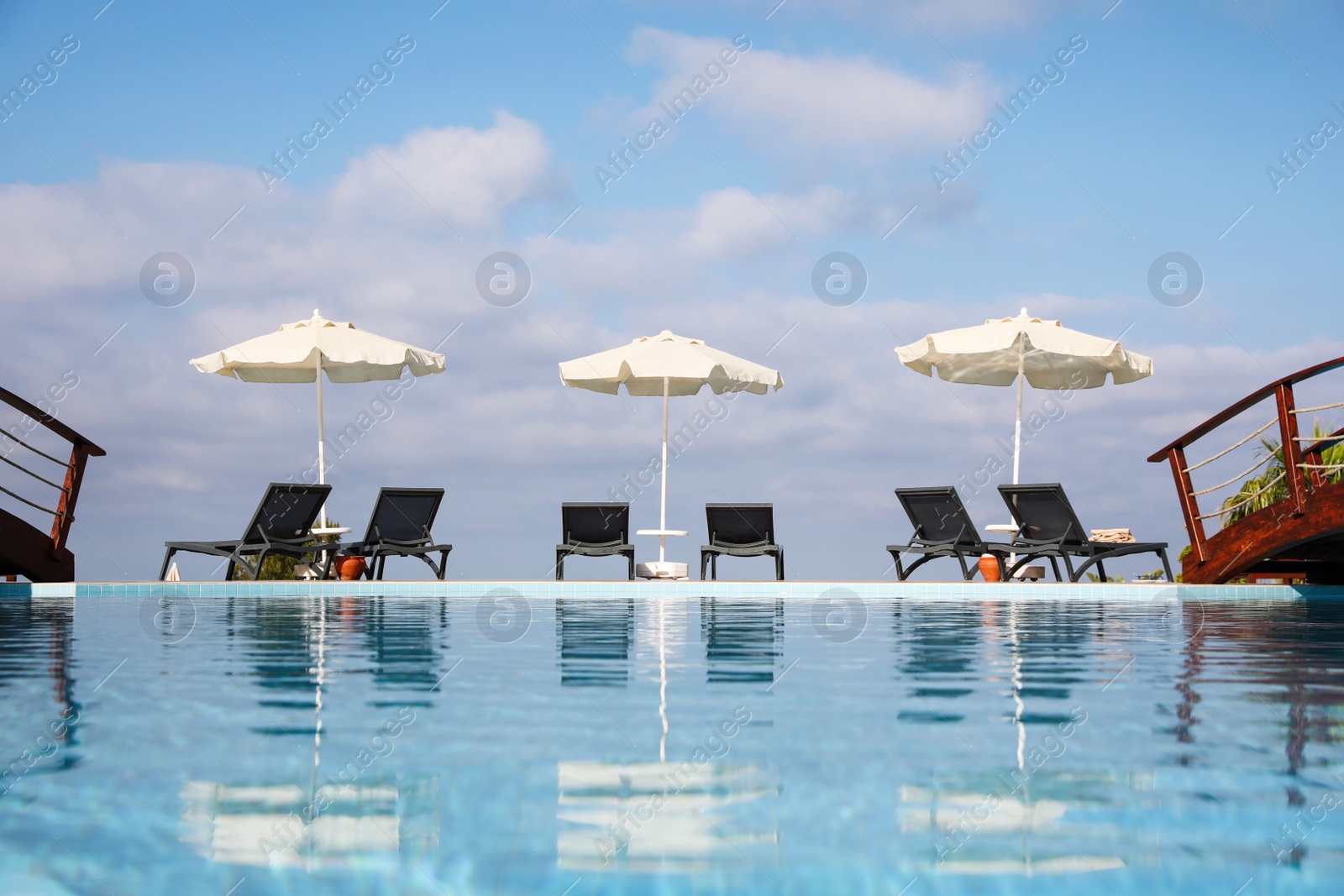 Photo of Chaise longues and beach parasols near outdoor swimming pool at resort