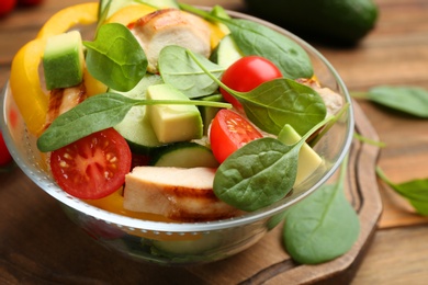 Photo of Delicious salad with chicken, vegetables and spinach on table, closeup