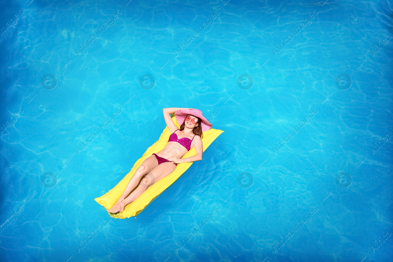 Photo of Young woman on inflatable mattress in swimming pool, above view