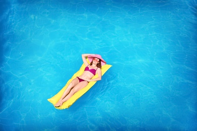 Photo of Young woman on inflatable mattress in swimming pool, above view