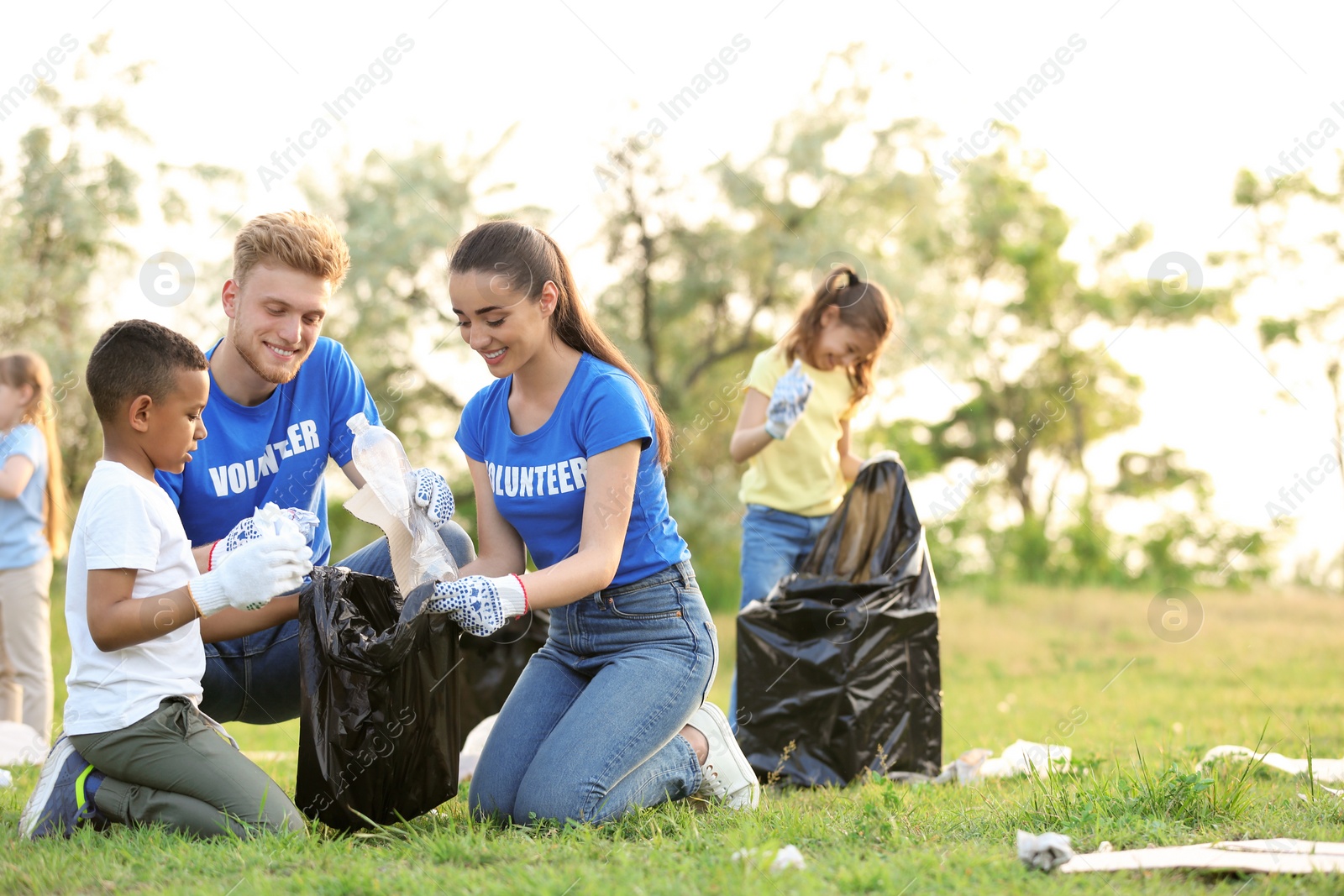Photo of Little African-American boy collecting trash with volunteers in park