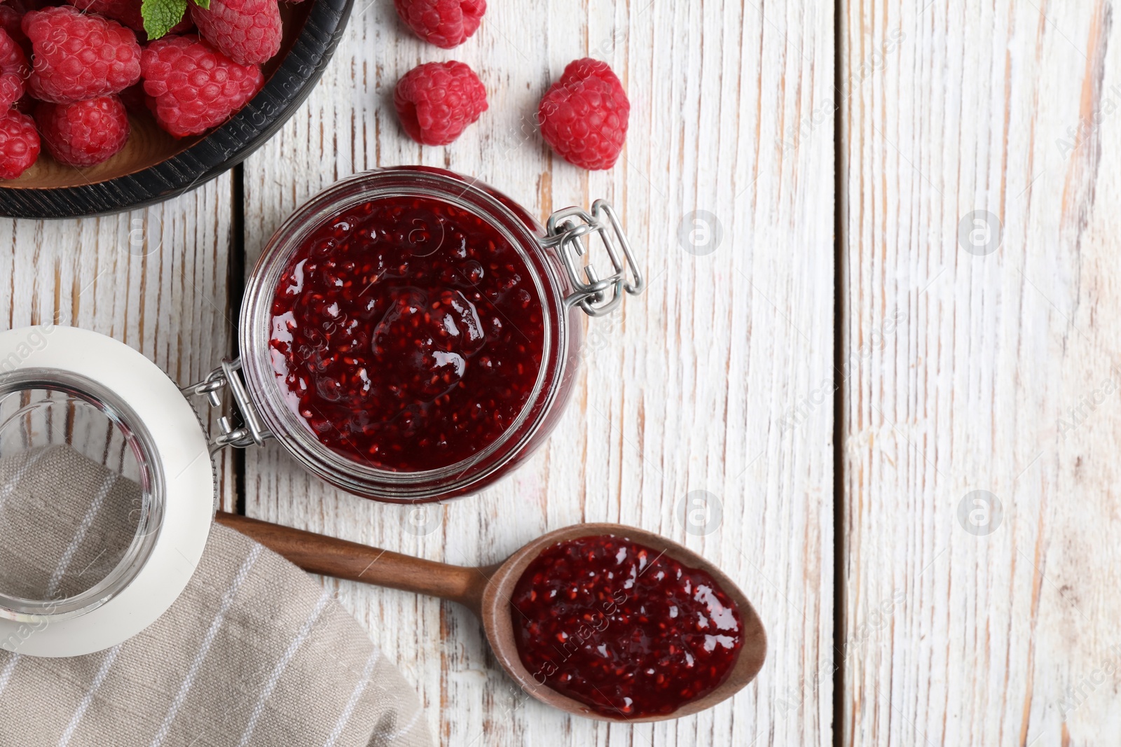 Photo of Flat lay composition with delicious raspberry jam on white wooden table. Space for text