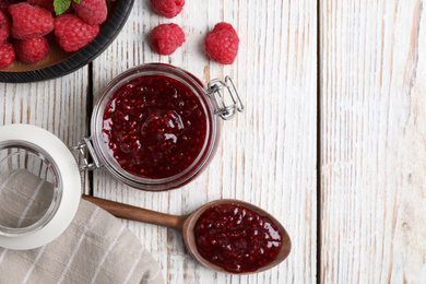 Flat lay composition with delicious raspberry jam on white wooden table. Space for text
