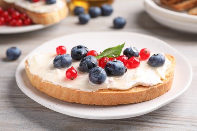 Photo of Tasty sandwiches with cream cheese and berries on white wooden table, closeup