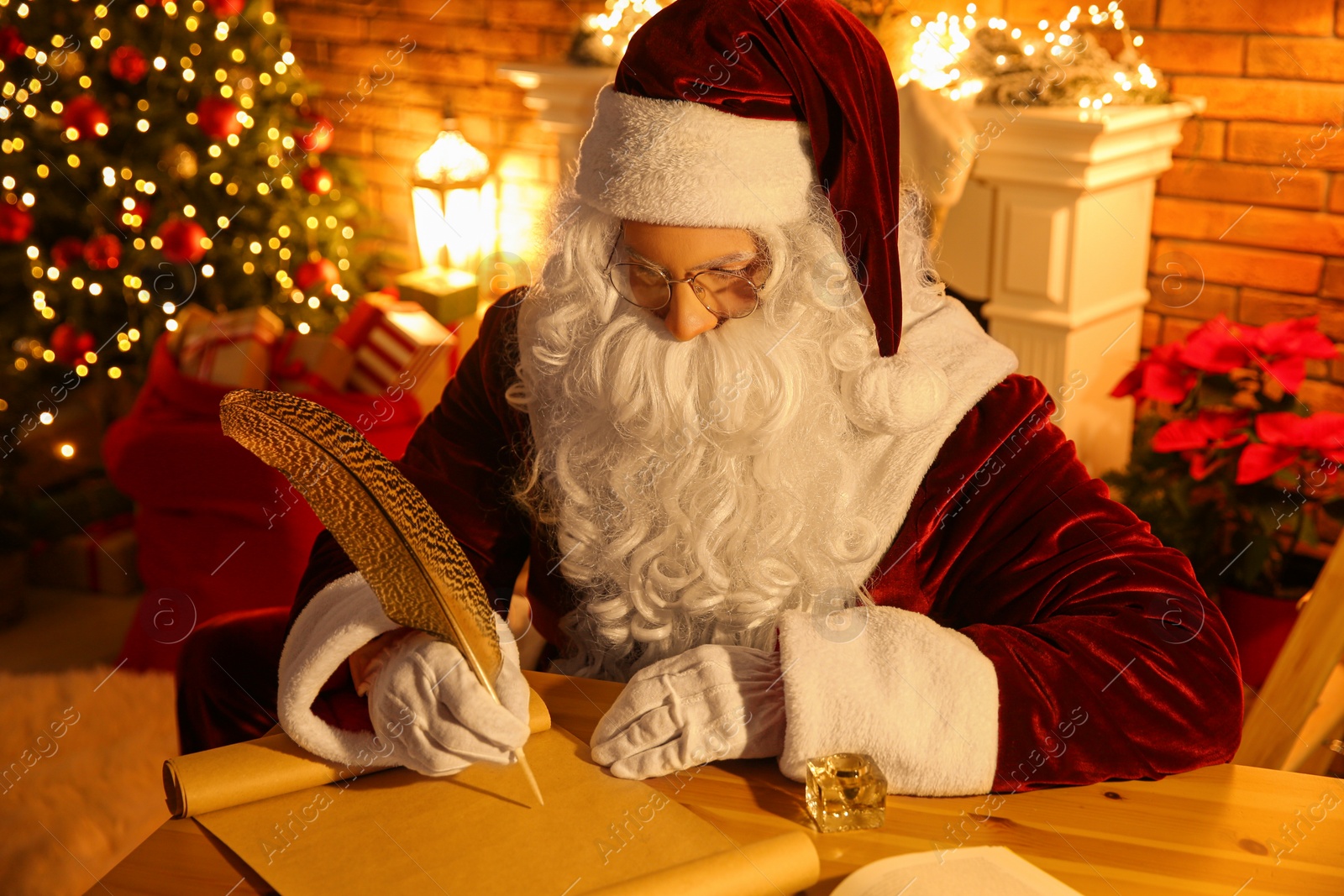 Photo of Santa Claus writing letter at table indoors