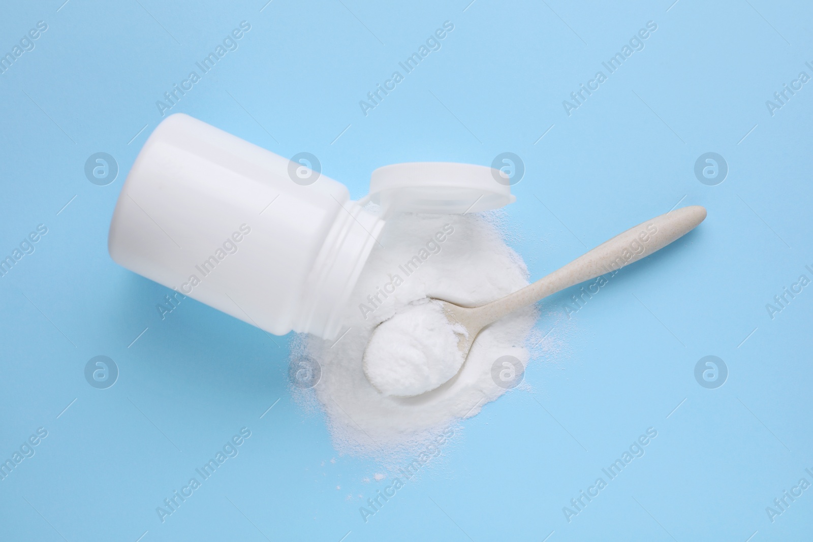 Photo of Jar with sweet powdered fructose and spoon on light blue background, top view