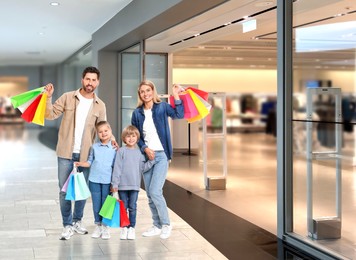 Image of Happy family with shopping bags walking in mall