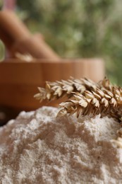 Photo of Pile of wheat flour and spikes against blurred background, closeup