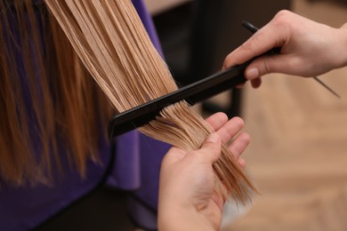 Photo of Stylist working with client in salon, closeup. Making haircut