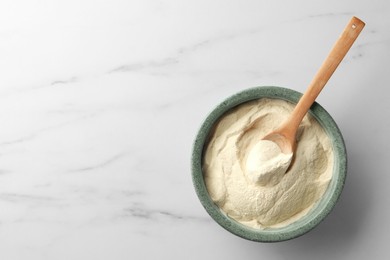 Photo of Bowl and spoon of agar-agar powder on white marble table, top view. Space for text