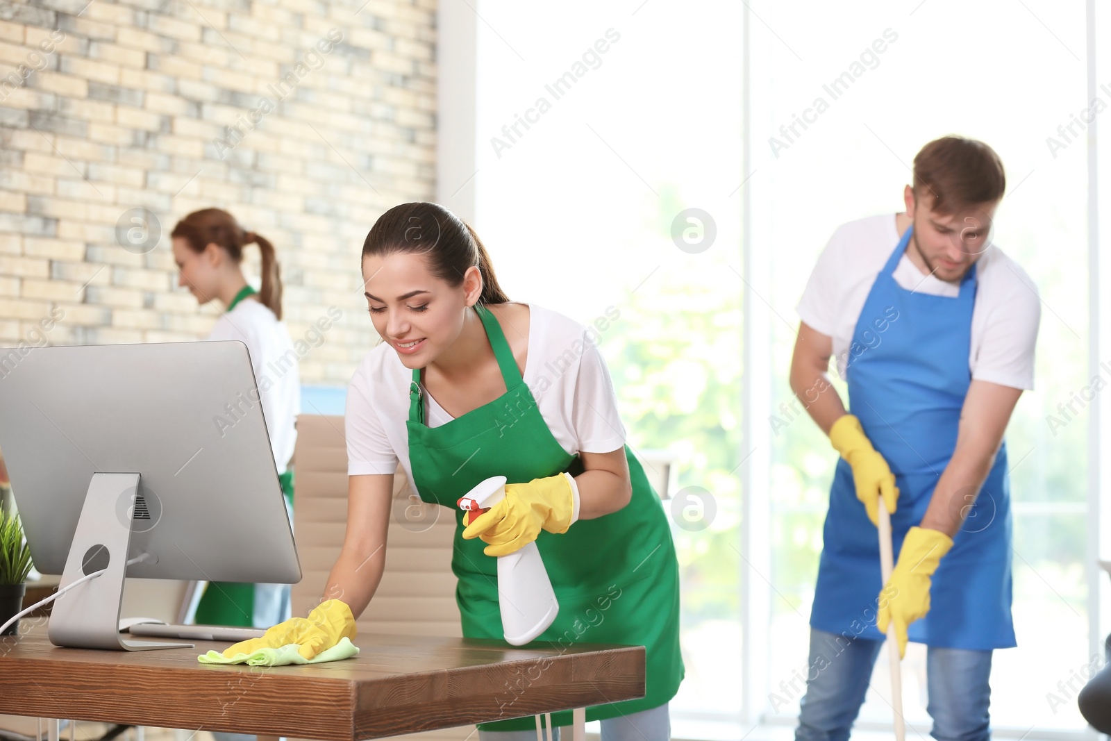 Photo of Team of professional janitors in uniform cleaning office