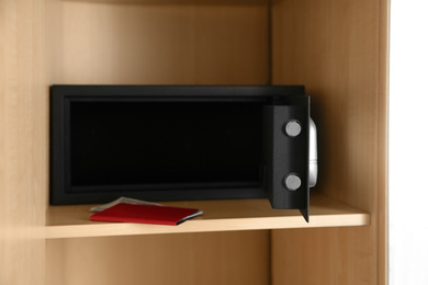 Photo of Open black steel safe in wooden closet