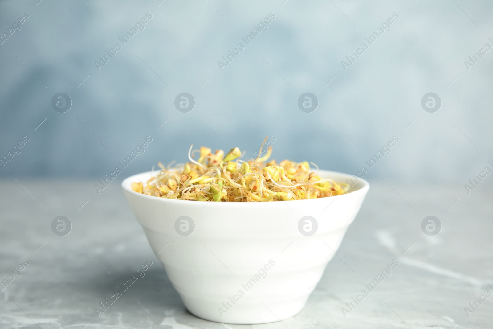 Photo of Bowl with sprouted green buckwheat on light grey table