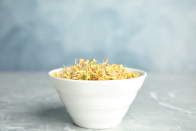 Photo of Bowl with sprouted green buckwheat on light grey table