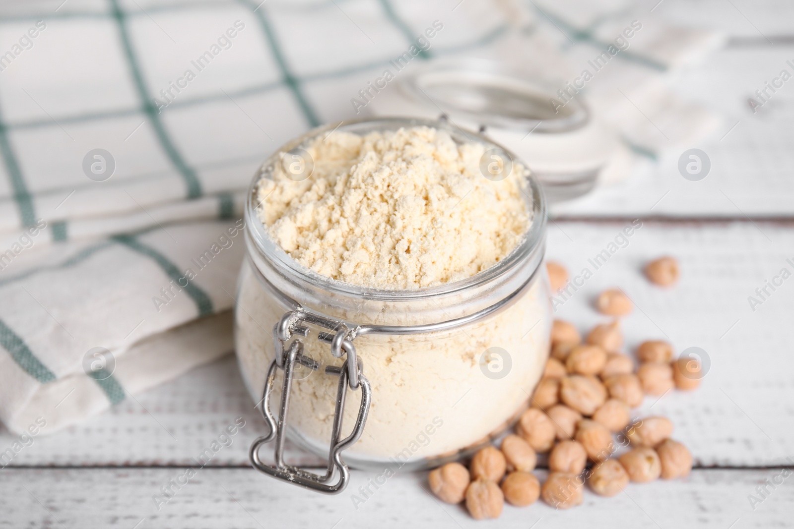 Photo of Glass jar with chickpea flour and seeds on white wooden table