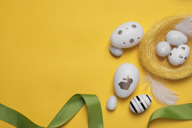Flat lay composition with festively decorated Easter eggs on yellow background. Space for text