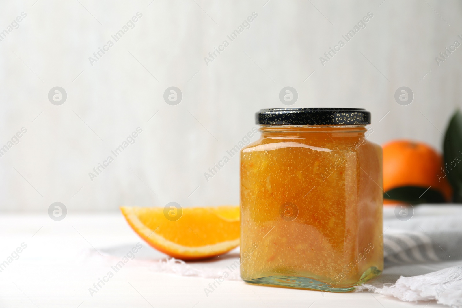 Photo of Delicious orange marmalade in jar on white table, space for text