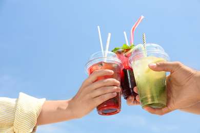 Photo of People with refreshing drinks against blue sky, closeup