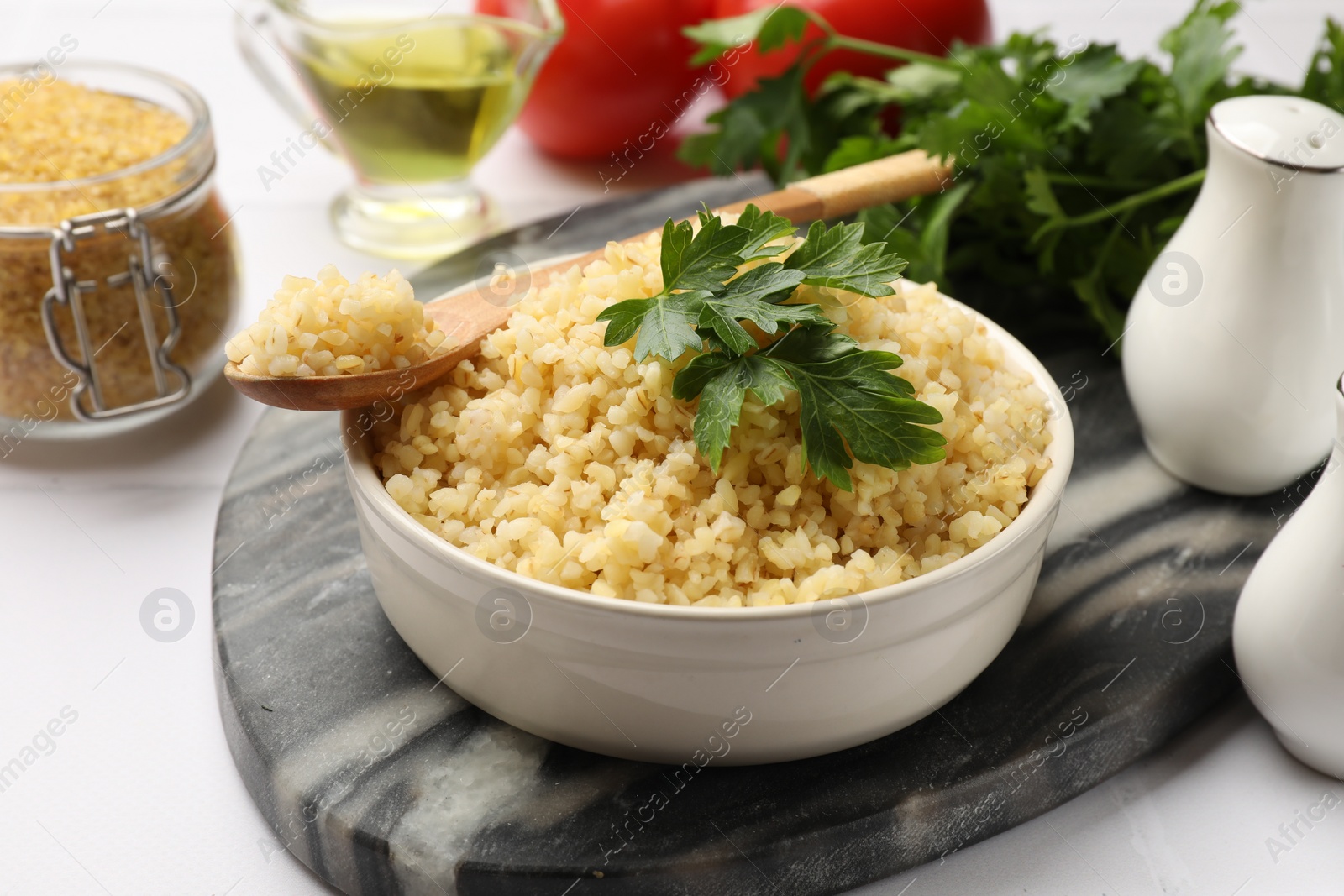 Photo of Delicious bulgur with parsley in bowl served on table, closeup