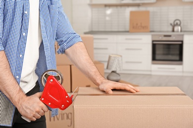 Photo of Man packing moving box indoors, closeup. Space for text