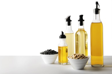 Bottles of different cooking oils and seeds on white background, space for text