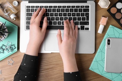 Photo of Woman typing on laptop at workplace, top view. Beauty blogger