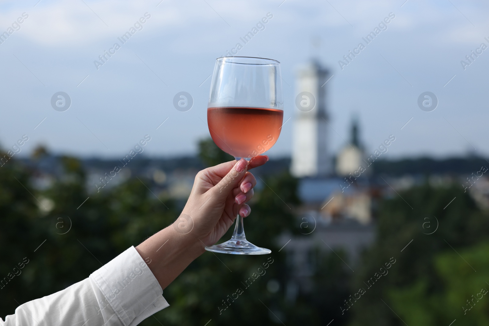 Photo of Woman holding glass of rose wine outdoors, closeup