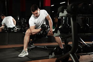 Photo of Man working out with dumbbell in modern gym