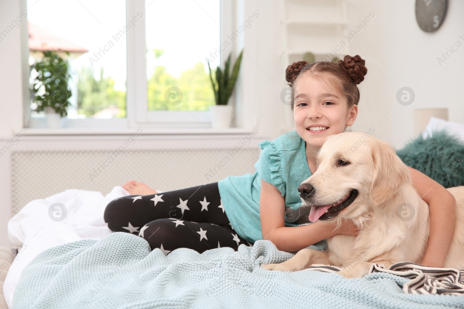 Photo of Cute little child with her pet on bed at home