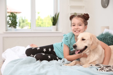 Photo of Cute little child with her pet on bed at home