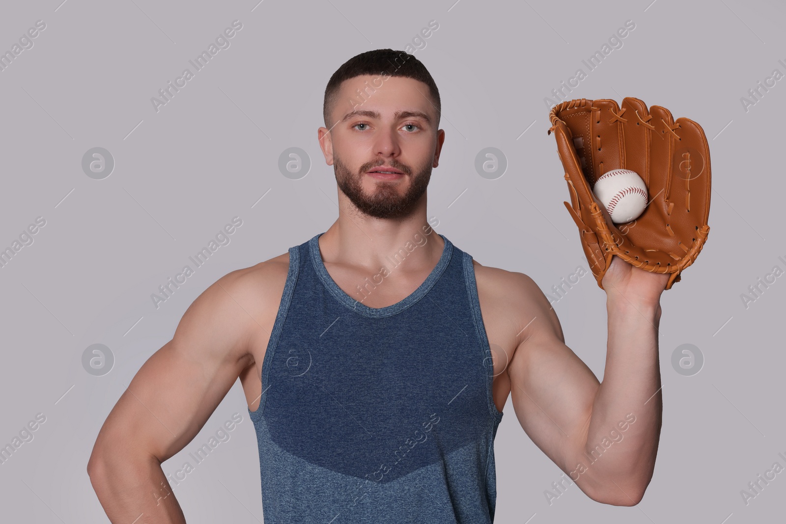 Photo of Athletic young man with glove and baseball ball on light grey background
