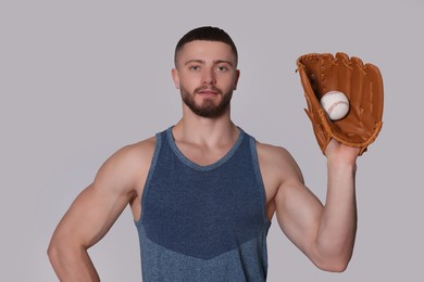 Photo of Athletic young man with glove and baseball ball on light grey background
