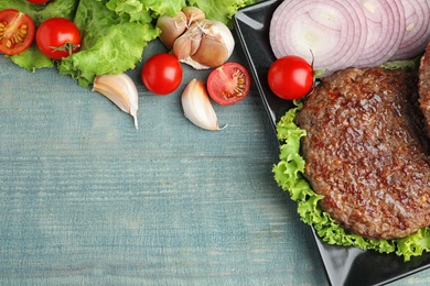 Photo of Flat lay composition with grilled meat cutlet for burger on blue wooden table. Space for text